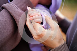Parents on a walk with a baby in the autumn park. Mother holds the baby's hand. Hands shot close up