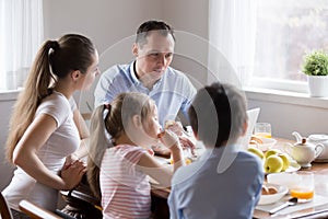 Parents watching computer while children eating breakfast at kitchen