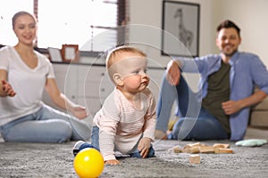 Parents watching their baby crawl on floor