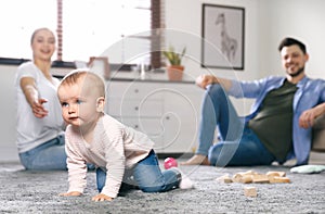 Parents watching their baby crawl on floor