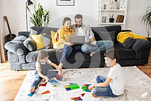 Parents working on the distance during quarantine. Father and mother work remotely with laptops sitting on the couch in