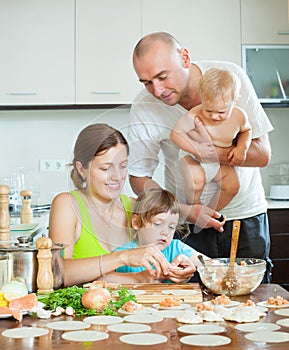 Parents with young children dumplings fish cooking in a home kit