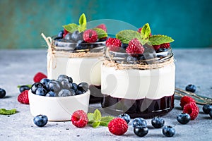 Parfait with cream and fresh berries in the glass jar.