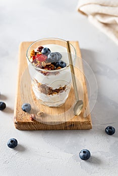 Parfait. Glass with homemade granola with yogurt and fresh berries on white concrete background. Dieting, recipe