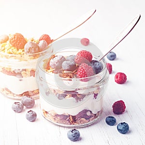 Parfait with granola, berries and yogurt in jars.