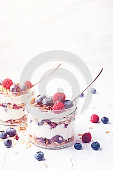 Parfait with granola, berries and yogurt in jars.