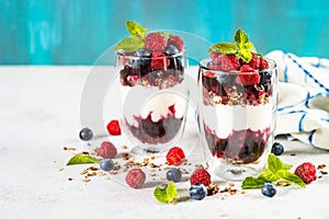 Parfait with granola, jam and fresh berries in the glass jar.