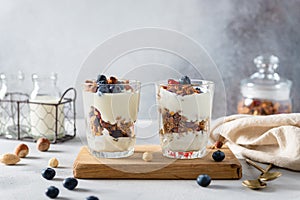 Parfait. Two Glasses with homemade granola with yogurt and fresh berries on gray concrete background.Side view, copy space.