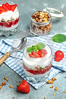 Parfait with yogurt, granola, jam, fresh berries and mint leaves in glass jar. gluten free diet, Healthy breakfast. vertical image