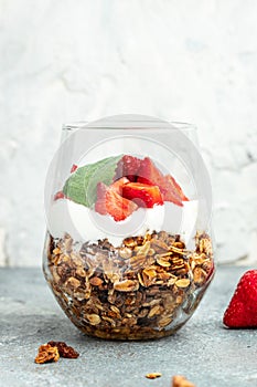 Parfait with yogurt, granola, jam, fresh berries and mint leaves in glass jar. gluten free diet, Healthy breakfast. vertical image