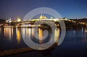 Pargue charles bridge and prague castle by night reflections river with boat motive in the front