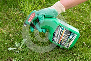 Paris, France - August 15, 2018 : Gardener using Roundup herbicide in a french garden. Roundup is a brand-name of an herbicide con