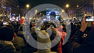 PARIS, FRANCE - DECEMBER, 31, 2016. Crowded Champs-Elysees street and light show on famous triumphal arch, Arc de