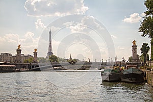 A few barges and Alexander the Third Bridge on the background of the Eiffel Tower in Paris