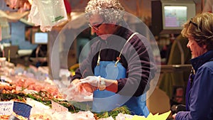 PARIS, FRANCE - OCTOBER 7, 2017. Vendor packing shrimps at fish and seafood stall at the local food market