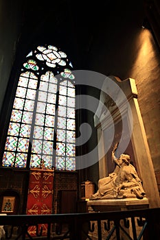 Paris, France - October 28, 2018: Interior of Notre Dame de Paris. Small altar with ancient statue of saint and stained glass