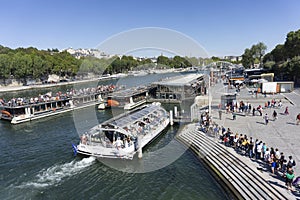 PARIS, FRANCE - SEPTEMBER 15, 2019: Tourists are waiting in a long line on the bank of Seine river to board on a cruise boat