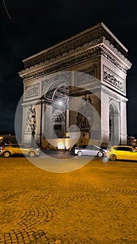 PARIS - March 10, 2023: The Arch of Triumph of the Star The Arc de Triomphe de l'Etoile and traffic lights at night. Paris