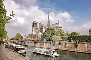 Paris, Notre Dame cathedral with tourboat on Seine river in France