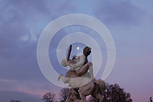 Paris statue framing the moon in the Tuilleries photo