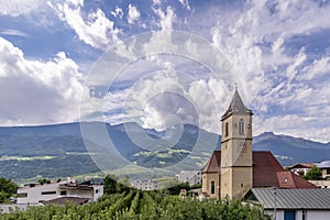 The parish church Pfarrkirche St. Johannes der TÃÂ¤ufer in Corzes, South Tyrol, Italy, against a dramatic sky photo