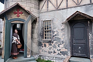 Parishioner in vintage clothes at the entrance to the retro Church with a large red cross over the door