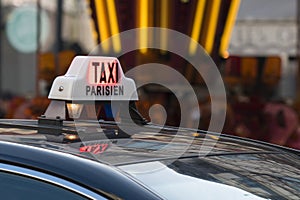 Parisian Taxi sign and car circulating with customer in the Paris streets