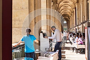 Parisians and tourists enjoy summer day drinks in cafe on a terrace of Louvre