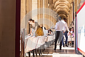 Parisians and tourists enjoy summer day drinks in cafe on a terrace of Louvre