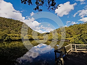 Beautiful morning view of a creek with reflections of deep blue sky, light clouds, mountains and trees