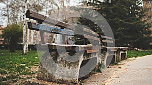 A park bench is empty and has a blue seat