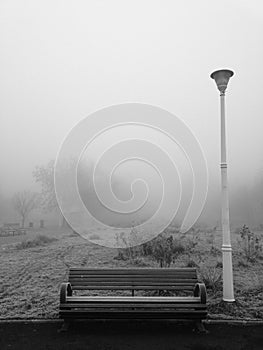 Park bench and pole in the freezing fog