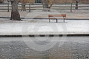 Park Bench by Pond In Winter snow