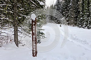 A park boundary signpost along a wintery hiking path in the snowy forests of Mount Fernie Provincial Park photo