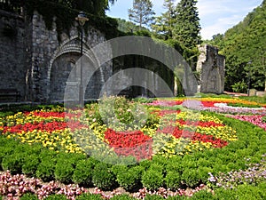 Park with flowers at summer, ornamental flowergarden next to ancient building
