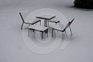 Park furniture chess table and chairs for four people made of light metal and wooden beams with backrest. on a bright snowy plain
