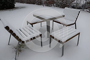 Park furniture chess table and chairs for four people made of light metal and wooden beams with backrest. on a bright snowy plain