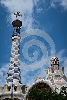 PARK GUELL, BARCELONA, CATALONIA: \'gingerbread house\' rooftop spire with cross and whimsical details, by Antoni Gaudi.