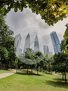 Park and Kuala Lumpur skyscrapers in sunny day. Twin towers in KL center