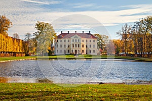 Park with a lordly castle behind a pond in autumn
