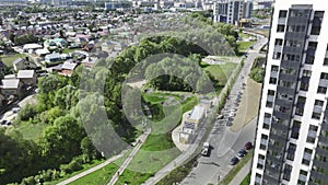 Park with lush trees near road with driving vehicles in city