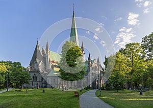 Park path meanders through a well-maintained cemetery, leading towards the majestic Nidaros Cathedral in Trondheim, Norway