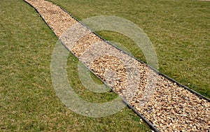 Park path in the outdoor fitness training center. The soft surface of the narrow jogging path is made of wood chips. flexible ecol