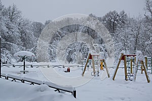 Park playground covered with fresh white snow after blizzard in winter