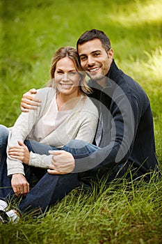 Park romance. Portrait of a loving young couple sitting on the grass in a park.