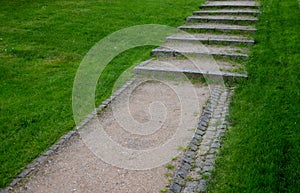 park stairs made of beige gravel material bordered by granite cubes follow the gravel path with a longitudinal groove of granite