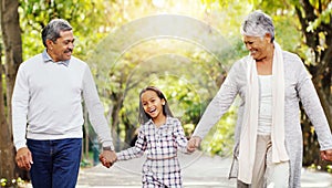 Park, walking and grandparents holding hands with kid, smile and bonding on outdoor adventure together. Old man, woman