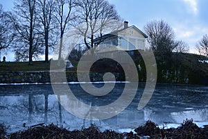 Park in winter with hause and iced pond