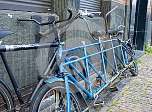 Parked against a red brick wall, a third bicycle securely locked in front