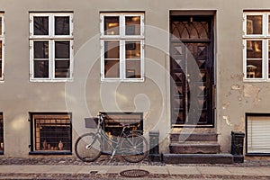 parked bicycle with basket near grey building with closed doors on street